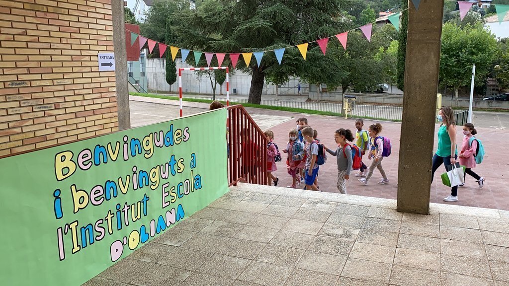 Pla obert del moment de l'entrada a l'Institut Escola d'Oliana (Alt Urgell) d'un grup d'alumnes en el primer dia de curs escolar, on es veu un cartell que els dona la benvinguda al nou institut escola. Imatge del 13 de setembre de 2021. (Horitzontal)