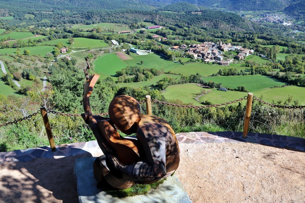 Pla general de l'escultura que s'ha inaugurat en homenatge a l'artista Pau Donés a Montanuy l'11 d'octubre del 2021. Primer pla de l'escultura i Montanuy al fons i les muntanyes araneses al fons. (Horitzontal)