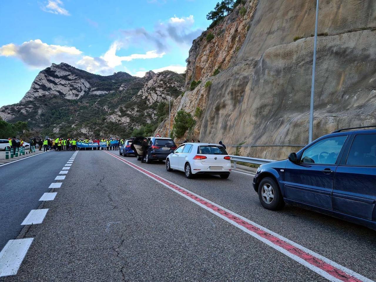 Primer pla de cotxes aturats i al fons els manifestants tallant la C-14. Imatge del 8 de desembre del 2021. (Horitzontal)