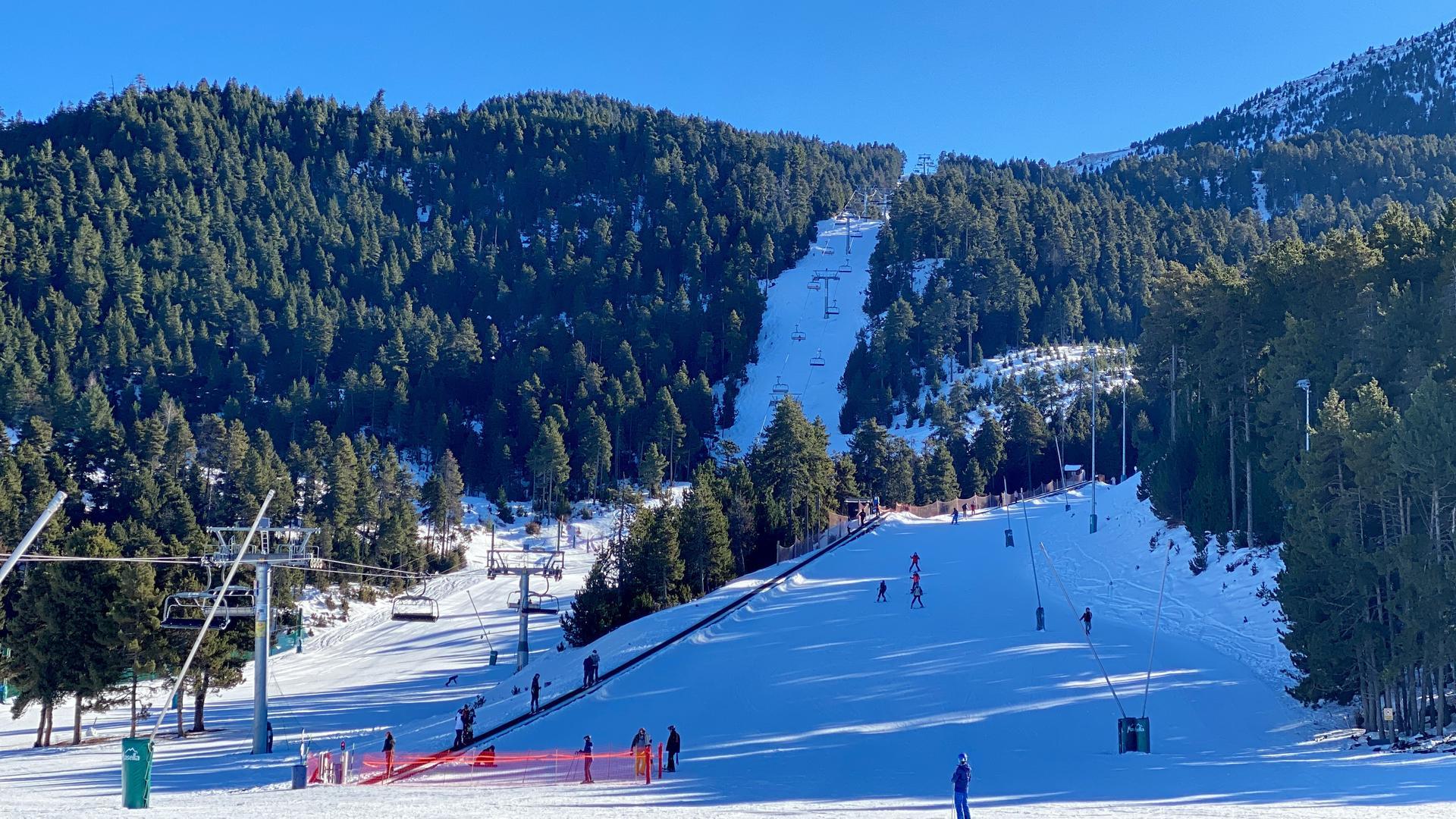 Pla obert de diversos esquiadors baixant per una de les pistes de Masella (Cerdanya) i altres persones pujades a un teleesquí de l'estació. Imatge publicada el 21 de desembre de 2021. (Horitzontal)