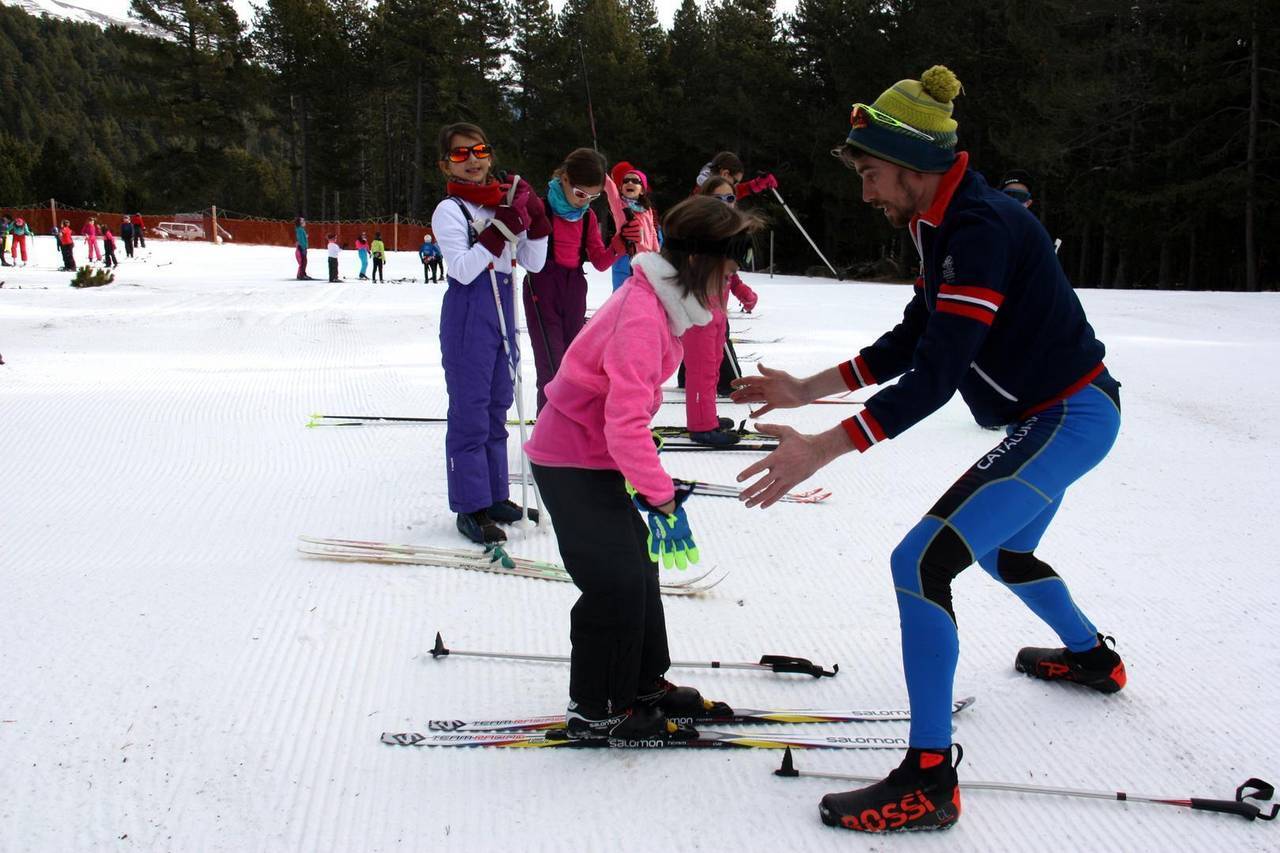 Pla general on es veu un dels monitors del programa Esport Blanc Escolar ajudant a una de les alumnes que estan aprenent esquí de fons a Aransa, a Lles de Cerdanya. Imatge del 13 de gener de 2020 (Horitzontal).